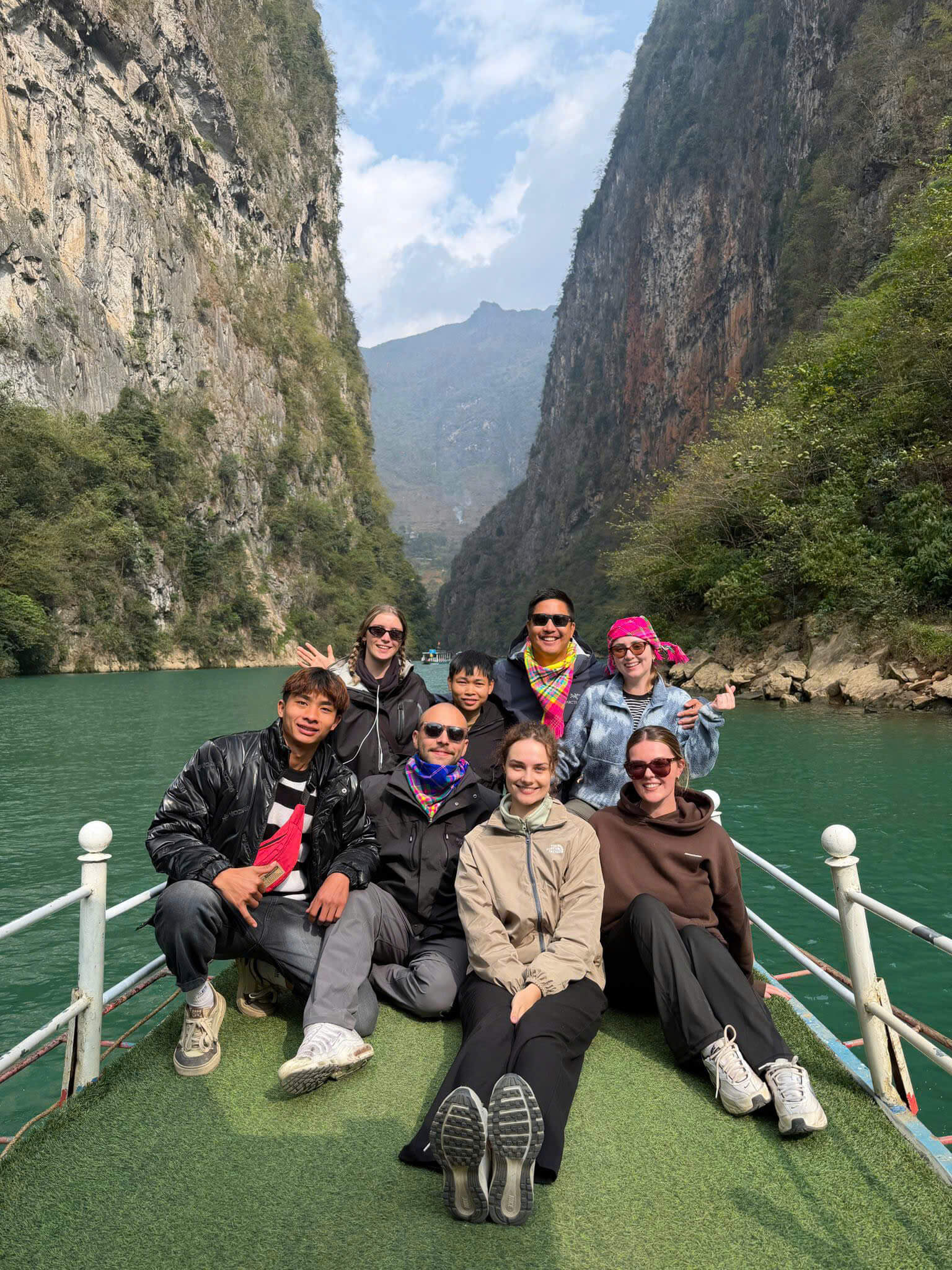 Travelers enjoying a boat trip on the emerald Nho Que River through Tu San Canyon, a must-do activity during the best time to visit Ha Giang Loop in spring or autumn.